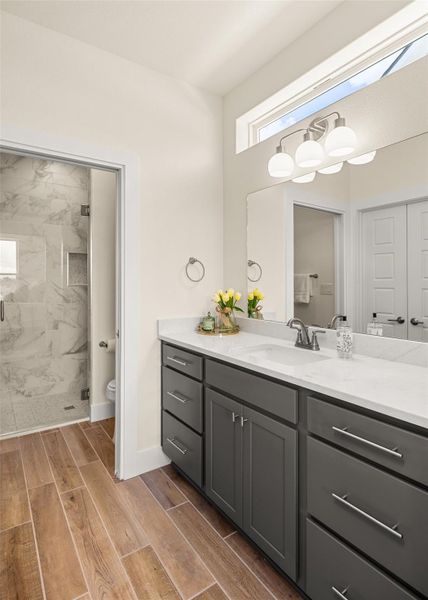Full bath featuring wood finish floors, vanity, and a marble finish shower
