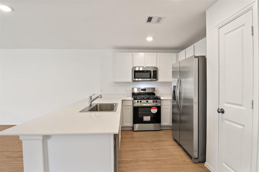 Bright, modern kitchen has crisp white cabinetry, sleek quartz-style countertops, and stainless steel appliances Bright, modern kitchen has crisp white cabinetry, sleek quartz-style countertops, and stainless steel appliances