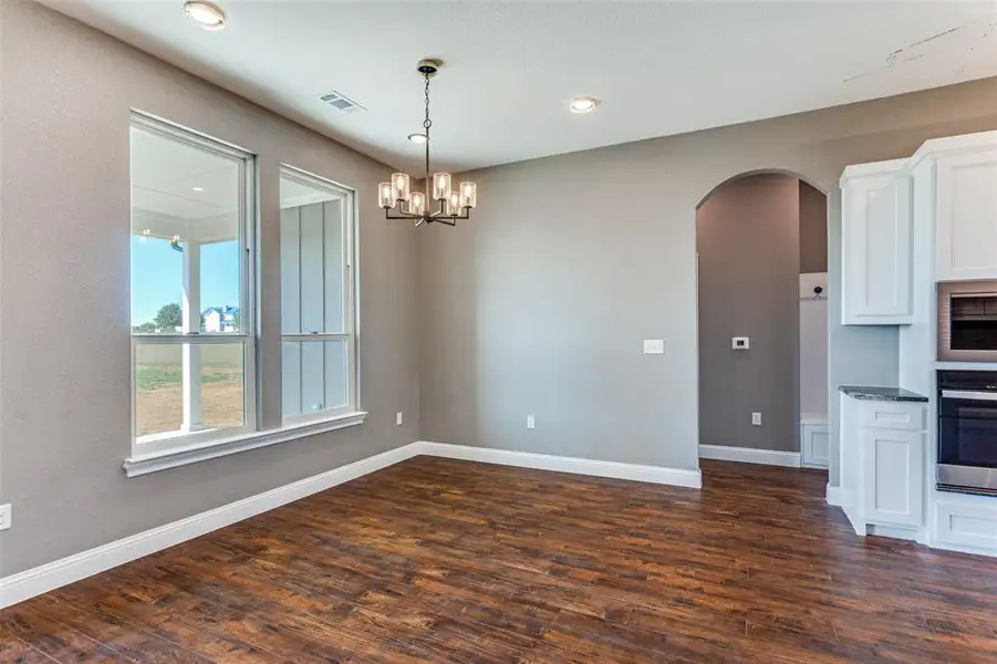 Kitchen featuring white cabinetry, arched walkways, dark wood-style floors, appliances with stainless steel finishes, and recessed lighting Kitchen featuring white cabinetry, arched walkways, dark wood-style floors, appliances with stainless steel finishes, and recessed lighting