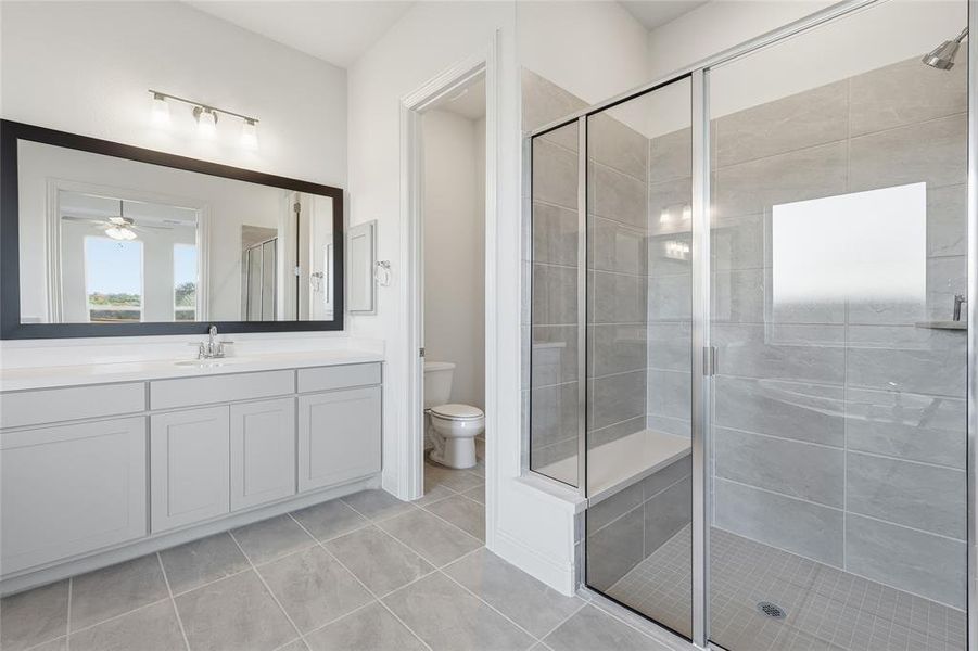 Full bathroom featuring a stall shower, vanity, a ceiling fan, and light tile patterned floors Full bathroom featuring a stall shower, vanity, a ceiling fan, and light tile patterned floors