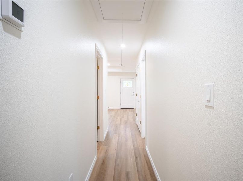 Hallway featuring wood-finish flooring, white painted walls, and a white entry door with decorative glass inserts