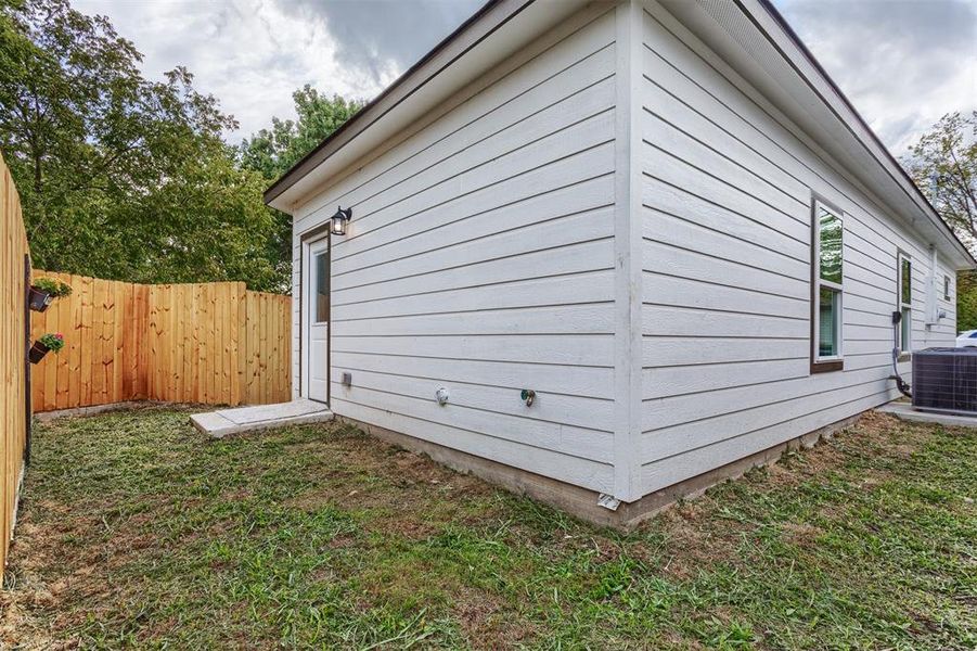 View of home's exterior featuring a lawn and central AC