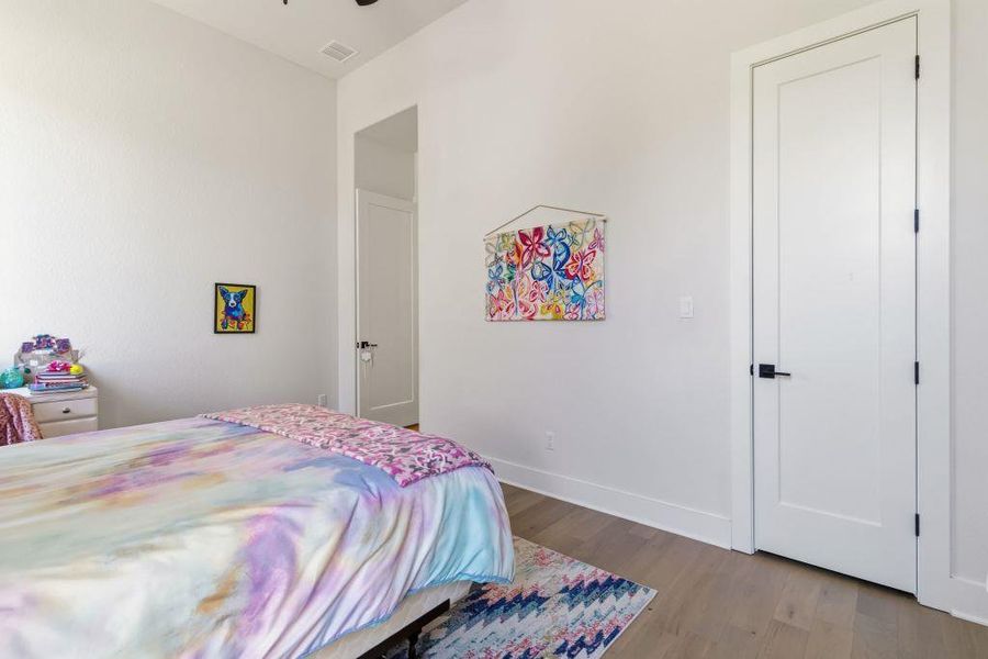 Hardwood floors and tall white doors define this comfortable bedroom space.