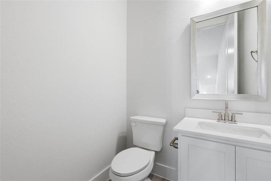 The bathroom features a white vanity with a rectangular sink and a silver-framed mirror, complemented by a white toilet