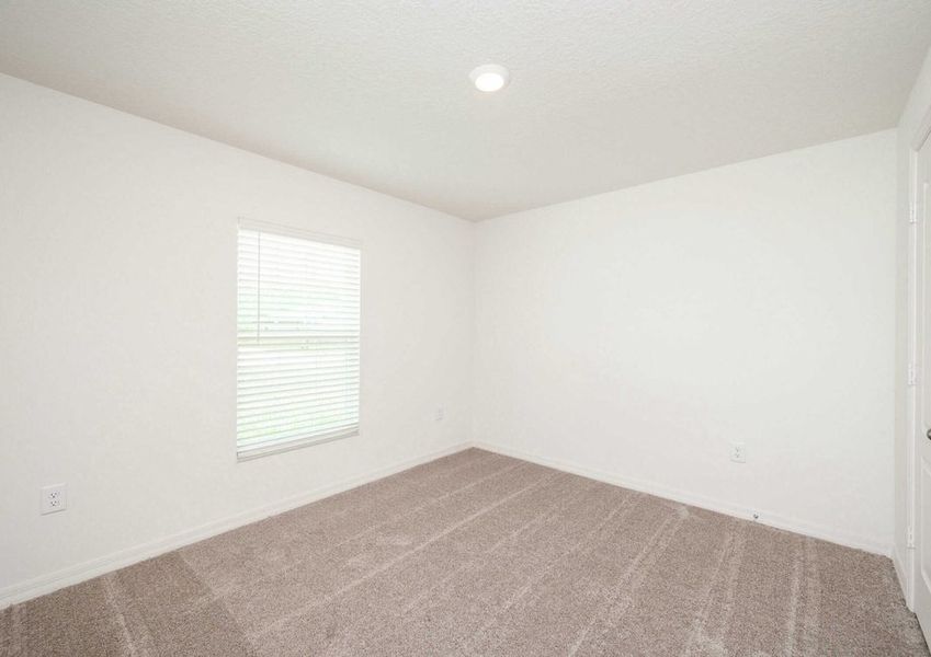 The secondary bedroom in the Caladesi floor plan with a ceiling light fixture, a single window and carpet flooring.