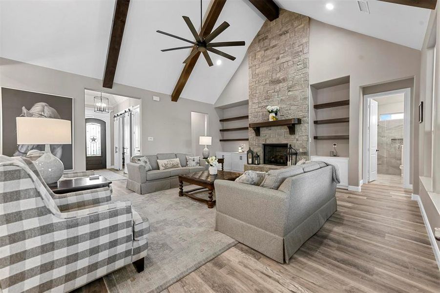 Living room with a wealth of natural light, wood-type flooring, a fireplace, and high vaulted ceiling