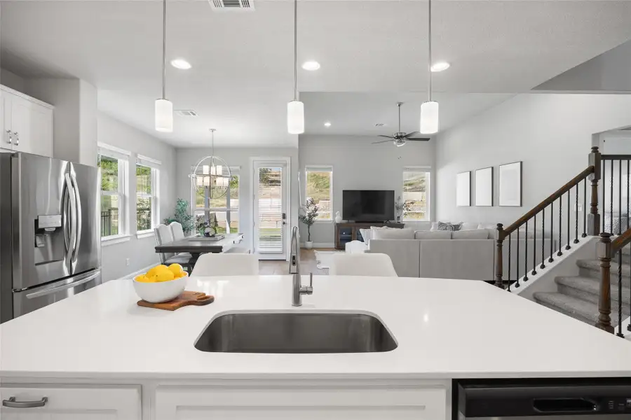 Kitchen with light countertops, stainless steel fridge, white cabinetry, pendant lighting, and recessed lighting