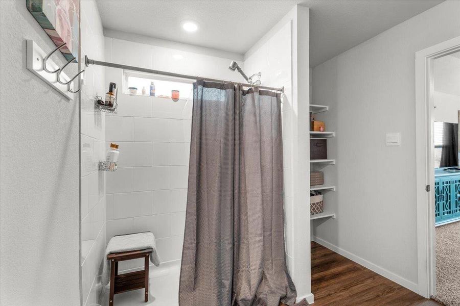 Bathroom with a shower stall and dark wood-style flooring