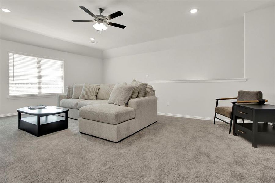 Carpeted living room featuring ceiling fan