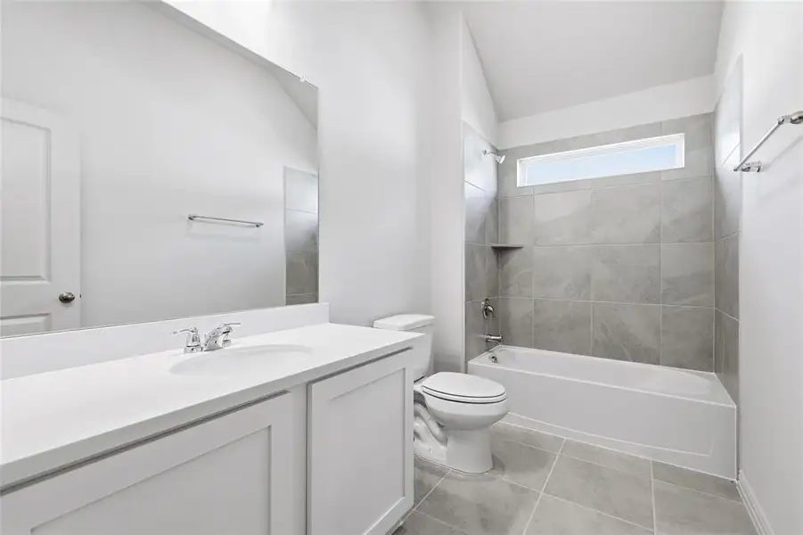 Bathroom featuring bathing tub / shower combination, vanity, light tile patterned floors, and vaulted ceiling Bathroom featuring bathing tub / shower combination, vanity, light tile patterned floors, and vaulted ceiling