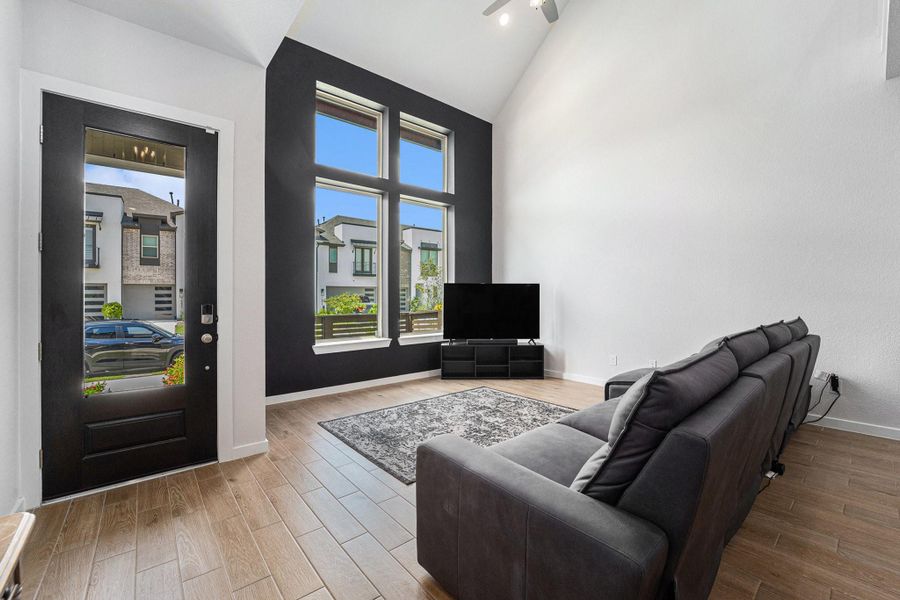 Spacious living area with dramatic ceilings and sleek glass-panel front door.