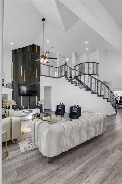 Living room with ceiling fan, hardwood / wood-style floors, and a high ceiling