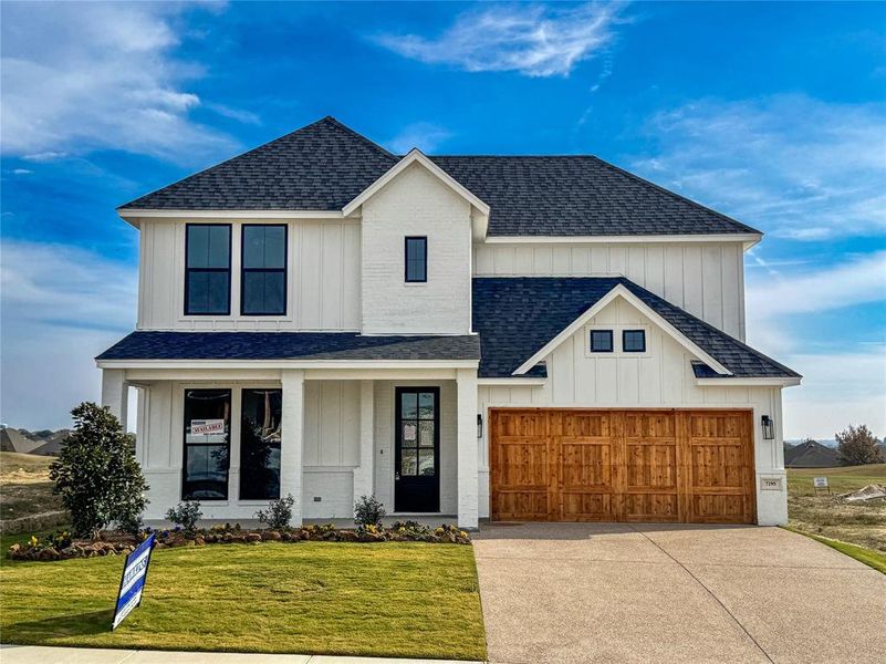 Modern inspired farmhouse featuring a shingled roof, a porch, board and batten siding, and a front lawn
