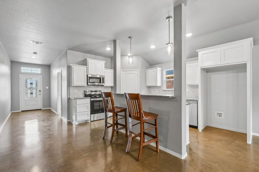 An open concept kitchen features stainless steel appliances, granite countertops, and a breakfast bar. An open concept kitchen features stainless steel appliances, granite countertops, and a breakfast bar.