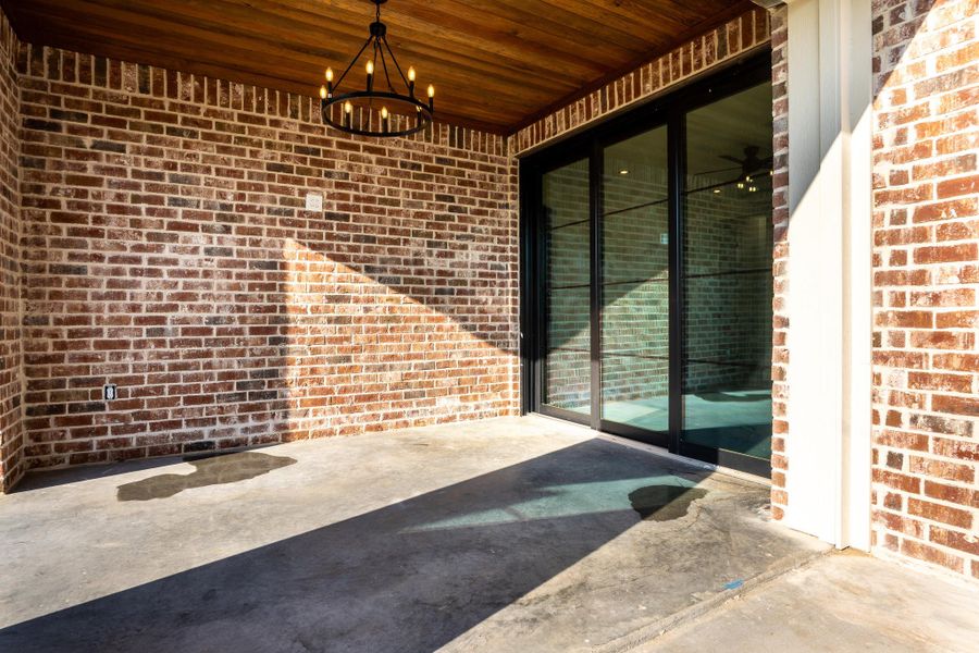Property entrance featuring brick siding and a patio