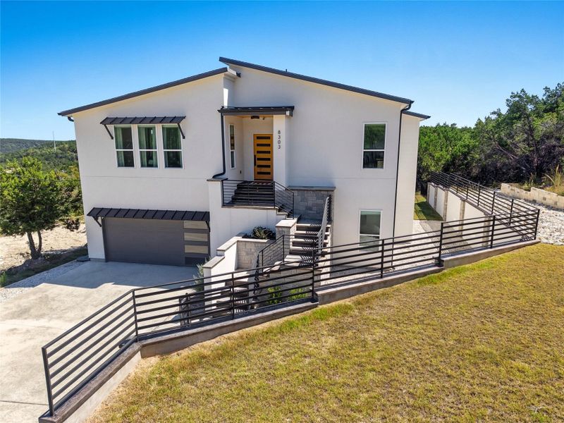 Contemporary house with stucco siding, concrete driveway, an attached garage, a balcony, and stone siding
