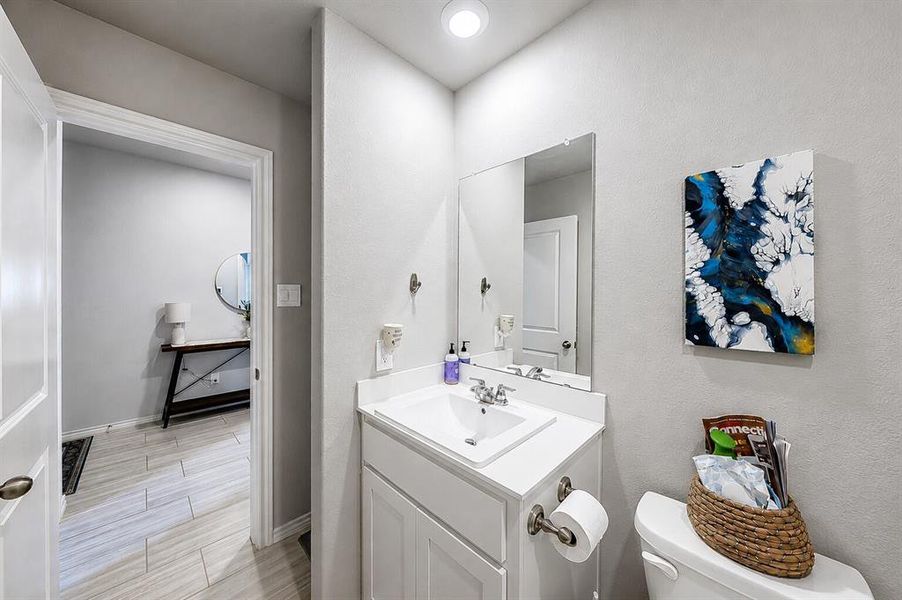 Bathroom featuring a white vanity with an integrated sink, polished chrome faucet, and a wall-mounted mirror