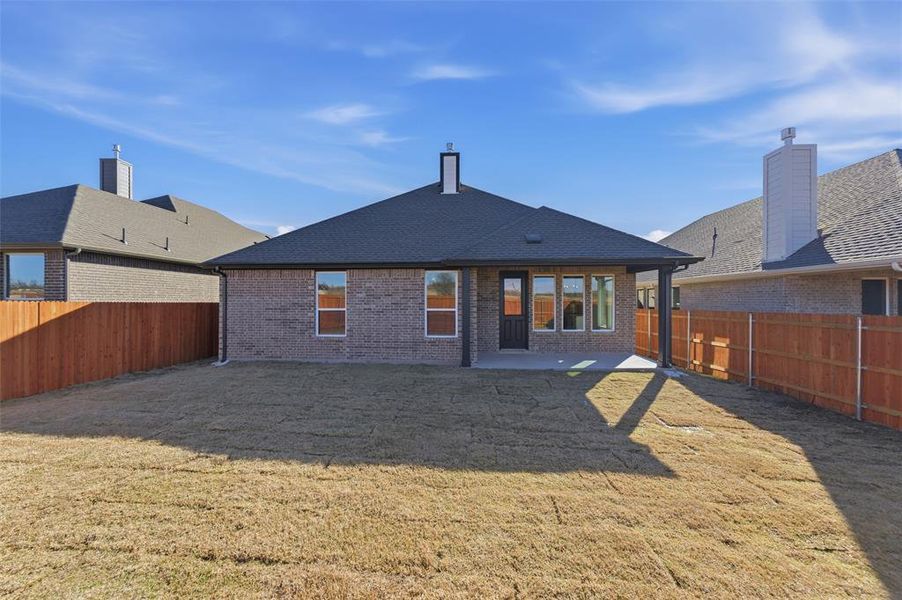 Back of house featuring brick siding, a patio, and a fenced backyard