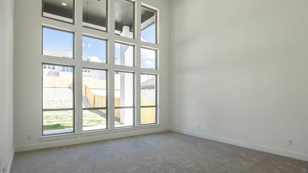 Carpeted spare room featuring a towering ceiling and baseboards