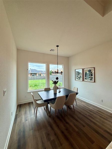 Dining area featuring wood-finish flooring, a contemporary chandelier, and two large windows