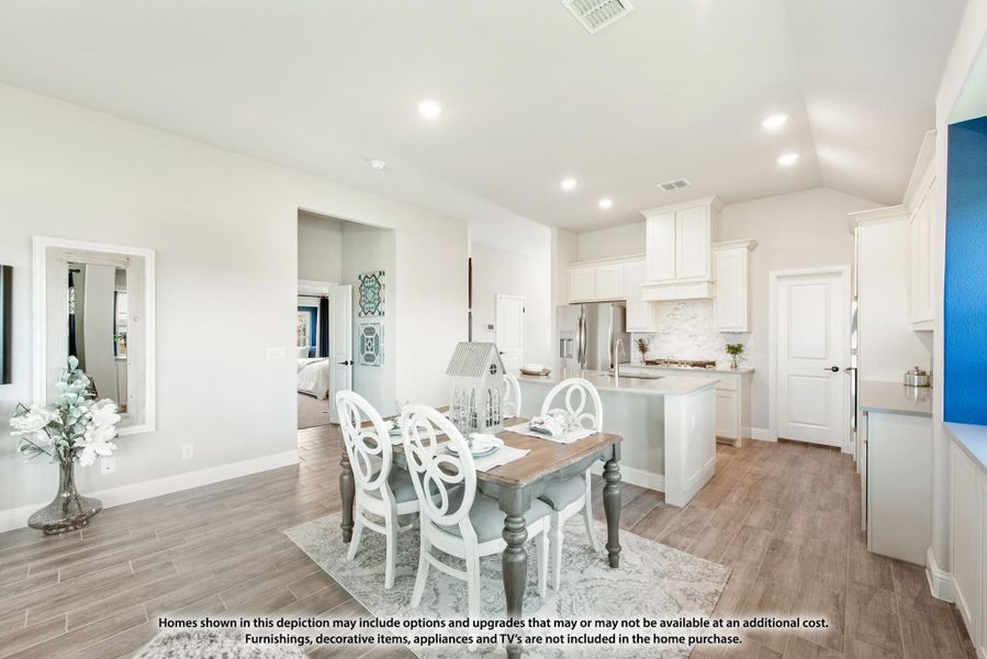 Open dining area with wood-look floors and white kitchen with island visible in background