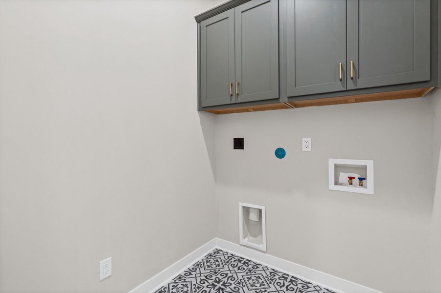 Utility area featuring patterned floor tiles and grey shaker-style cabinetry with gold-tone hardware Utility area featuring patterned floor tiles and grey shaker-style cabinetry with gold-tone hardware