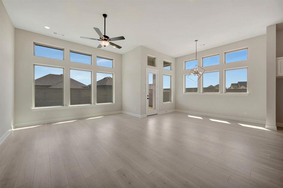 Spacious room featuring light wood-finish flooring, high ceilings, and extensive window arrays