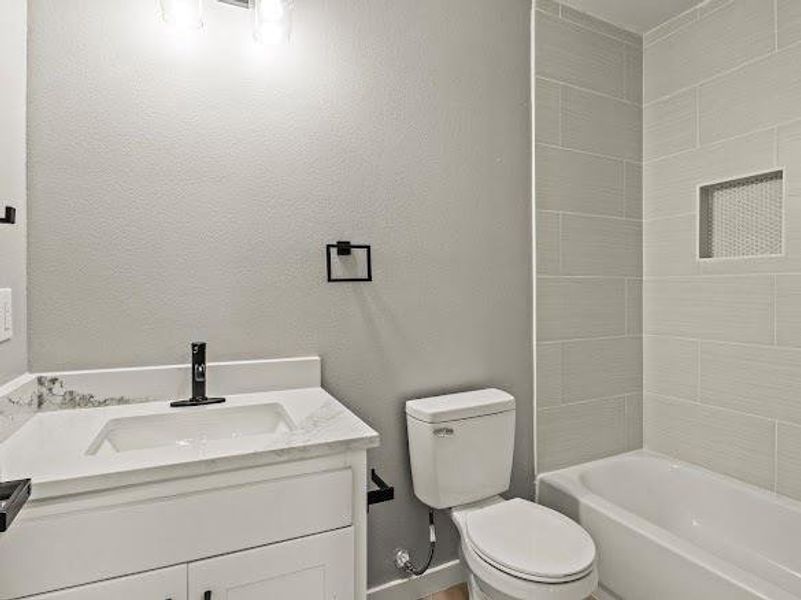 Bathroom with vanity, shower / bathtub combination, and a textured wall