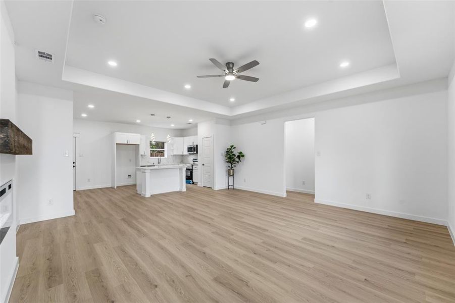 Expansive open-concept living area featuring light wood-finish flooring, a contemporary ceiling fan, and recessed lighting