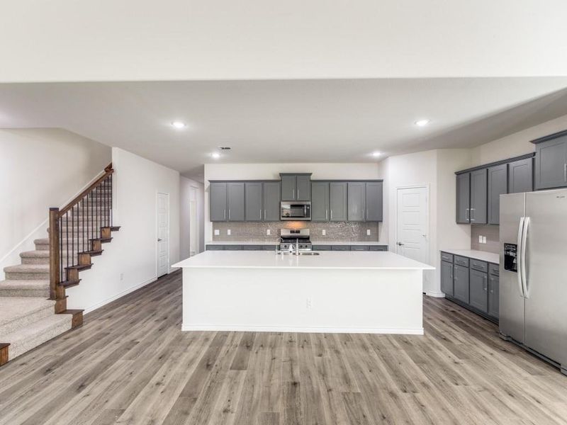 Kitchen featuring gray cabinetry, tasteful backsplash, appliances with stainless steel finishes, an island with sink, and recessed lighting