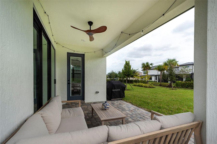 Covered outdoor patio with pavered floors wiht view to the back yard