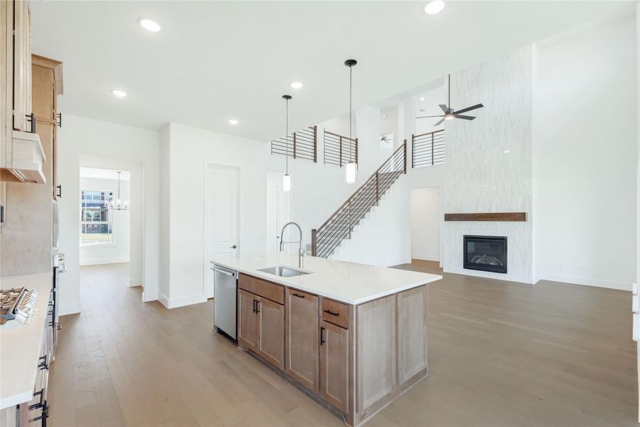 Open-concept kitchen with wood island, pendant lights, and fireplace visible in adjoining living area with staircase