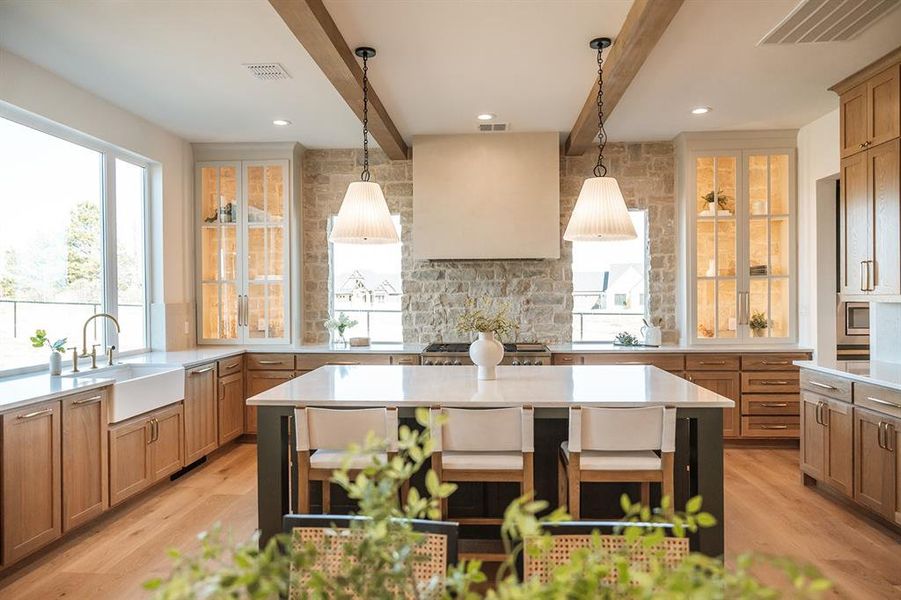 Kitchen with beamed ceiling, a kitchen island, decorative backsplash, light stone counters, and two tone cabinetry Kitchen with beamed ceiling, a kitchen island, decorative backsplash, light stone counters, and two tone cabinetry