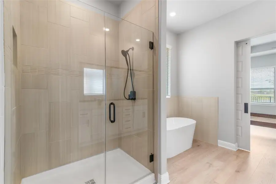 Luxurious primary bath with spacious shower and elegant soaking tub.