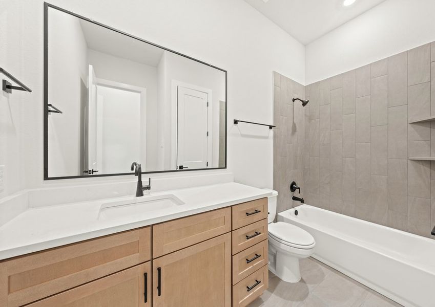 The secondary bathroom has a sprawling vanity space and a shower-tub combo.