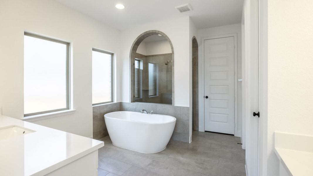 Bathroom featuring vanity, a freestanding bath, a tile shower, tile walls, and tile patterned flooring Bathroom featuring vanity, a freestanding bath, a tile shower, tile walls, and tile patterned flooring