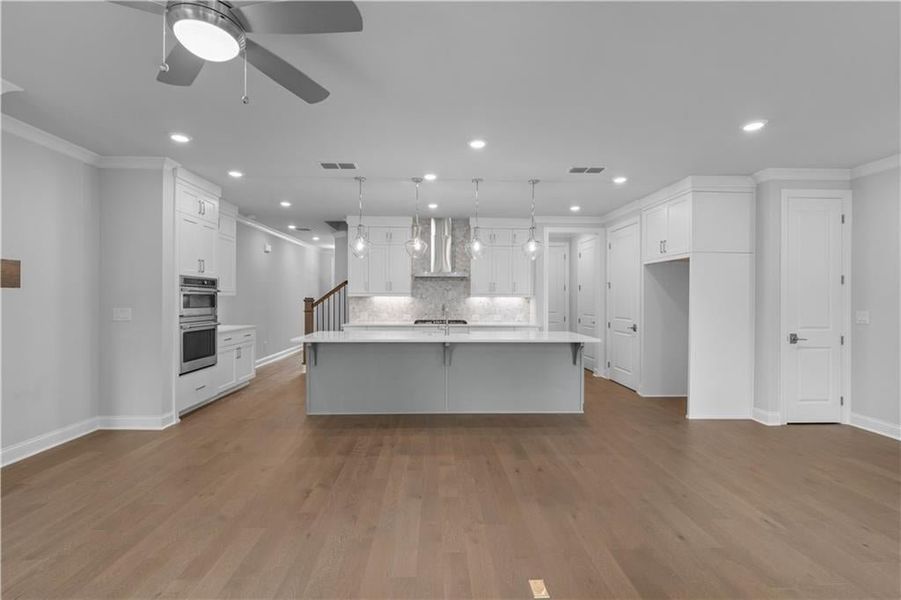 Kitchen with crown molding, a spacious island, white cabinetry, a breakfast bar, and hanging light fixtures Kitchen with crown molding, a spacious island, white cabinetry, a breakfast bar, and hanging light fixtures