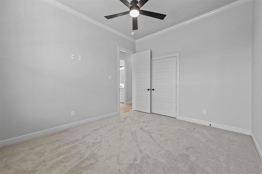 Unfurnished bedroom featuring light colored carpet, ceiling fan, and ornamental molding