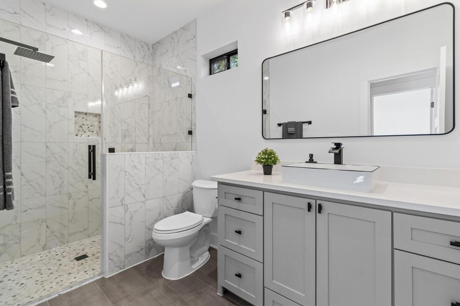 Bathroom with vanity, a marble finish shower, and recessed lighting
