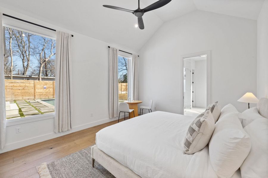 Bedroom featuring light wood-style floors, a ceiling fan, and a high ceiling