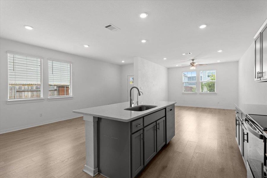 An open floorplan with recessed lighting and light hardwood flooring unifies this bright kitchen and living area.