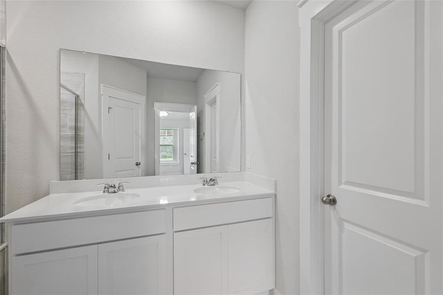Bathroom featuring double vanity and a tile shower Bathroom featuring double vanity and a tile shower