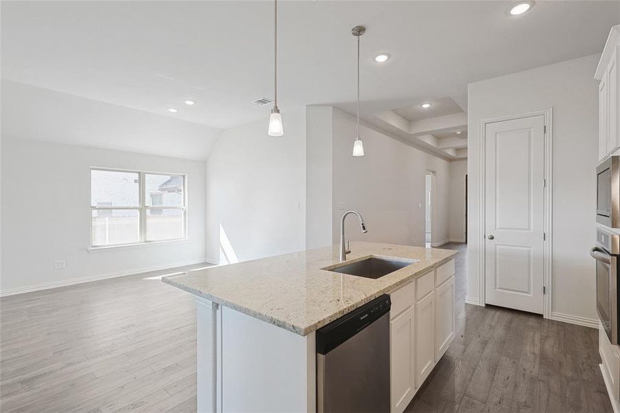 Kitchen with dishwasher, an island with sink, sink, decorative light fixtures, and white cabinetry