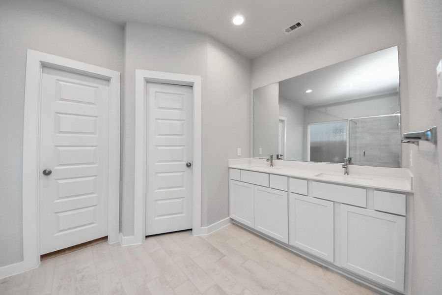Elevate your daily routine at the elegant vanity, now equipped with double sinks, light countertops, modern hardware, and beautiful recessed lights. Sample photo of completed home with similar floor plan. Actual colors and selections may vary.