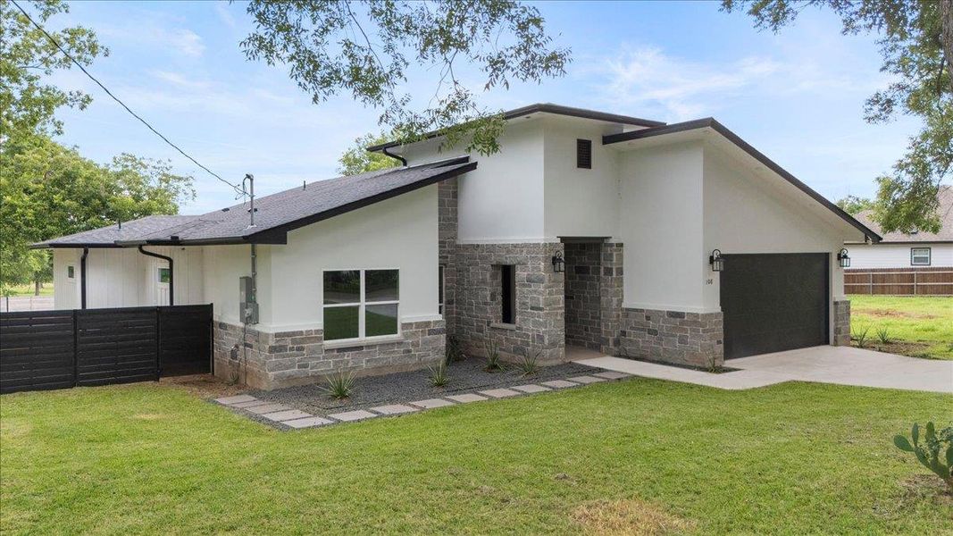 Rear view of property featuring stone siding, concrete driveway, an attached garage, stucco siding, and a shingled roof Rear view of property featuring stone siding, concrete driveway, an attached garage, stucco siding, and a shingled roof