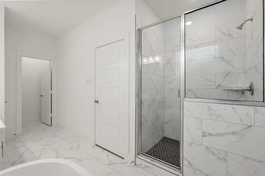 This luxurious Ensuite bathroom features a large separate shower with designer ceramic tile. It has a 42" freestanding Oval tub and white cabinetry with soft close door cabinetry and adjustable shelving & linen closet.