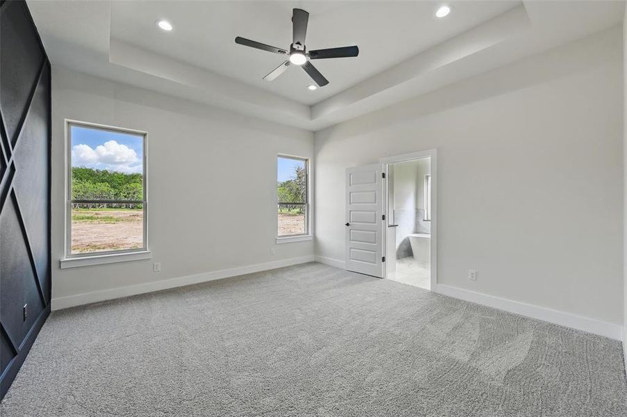 Unfurnished bedroom featuring a tray ceiling, carpet flooring, recessed lighting, baseboards, and ensuite bath Unfurnished bedroom featuring a tray ceiling, carpet flooring, recessed lighting, baseboards, and ensuite bath
