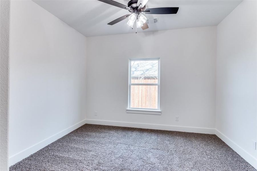 Carpeted empty room with ceiling fan, visible vents, and baseboards