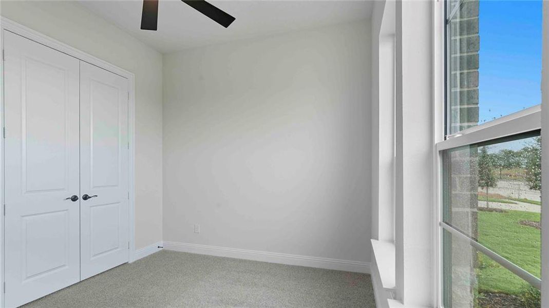 Neutral-toned room featuring a ceiling fan, light gray carpeting, and white baseboards