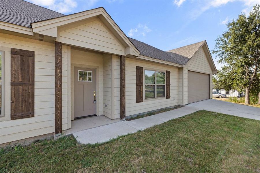 Doorway to property with a garage and a lawn